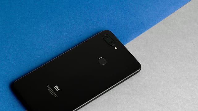 Modern black MI smartphone placed on a blue and gray background, showcasing technology elegance.