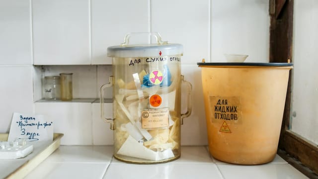 Two containers in a laboratory setting for managing radioactive waste disposal.