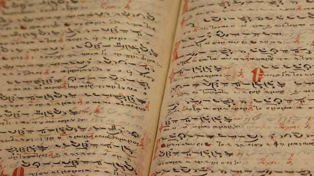 Close-up of an ancient manuscript with handwritten texts and ink inscriptions.