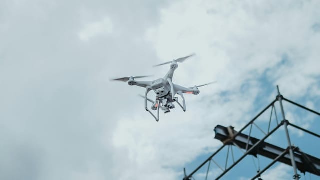 A drone hovering in the sky amidst clouds, showcasing technology in action.