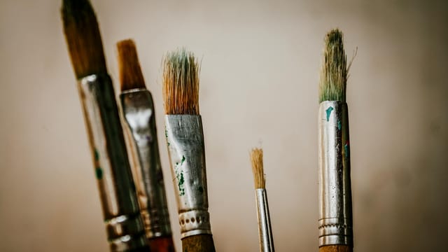 A detailed view of various paintbrushes used for artistic projects in a studio setting.