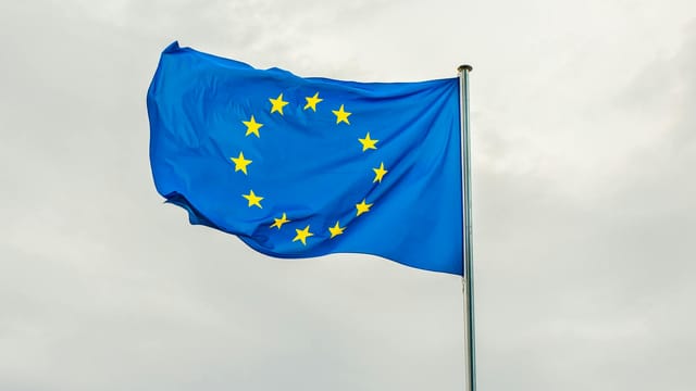 The European Union flag gracefully waving on a flagpole against a cloudy sky in Strasbourg, France.