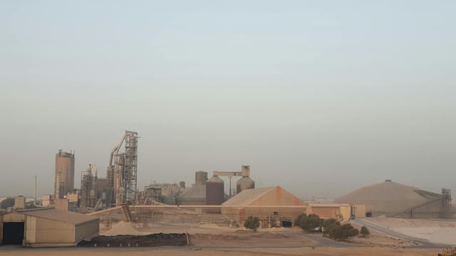 A vast industrial complex set in a desert environment under a clear sky.