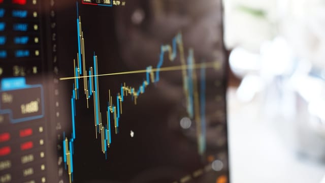 Detailed view of financial trading graphs on a monitor, illustrating stock market trends.