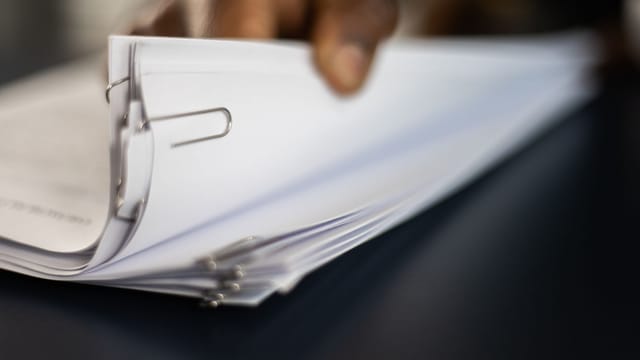 Detailed image of paper stacks held together by paperclips, showcasing organizational tools.