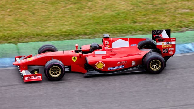 High-speed Formula 1 car in action on an outdoor racing track, showcasing motion and excitement.