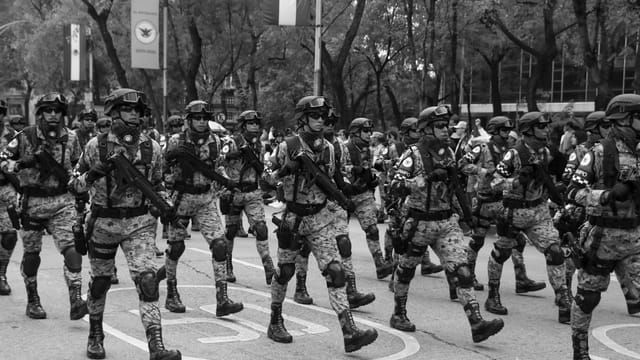 Mexican soldiers marching in formation during a military parade, showcasing discipline and unity.