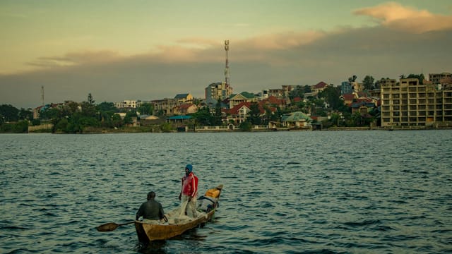 Two fishermen in a traditional wooden boat on Lake Kivu near Goma, DR Congo during sunset.