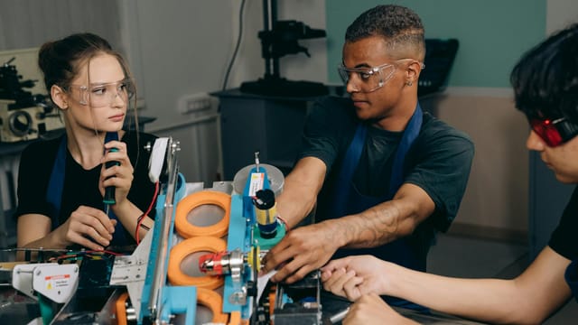 Three engineers collaborate on industrial machinery, emphasizing teamwork and technology in a manufacturing setting.