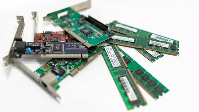 A detailed close-up of computer RAM sticks and PCI cards arranged on a white surface for tech illustration.