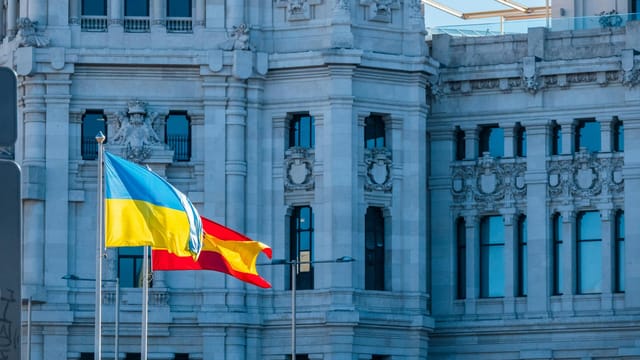 Spanish and Ukrainian flags flying outside a historic building in Madrid, Spain.