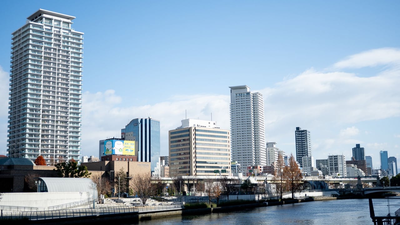 A vibrant urban skyline along a river in Osaka, Japan showcasing modern architecture.