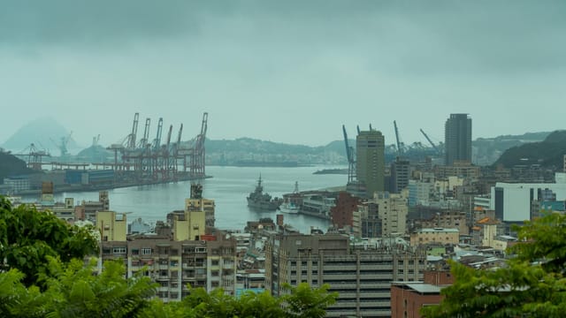 Scenic aerial view of Keelung Harbor, Taiwan with modern architecture and cranes under overcast skies.