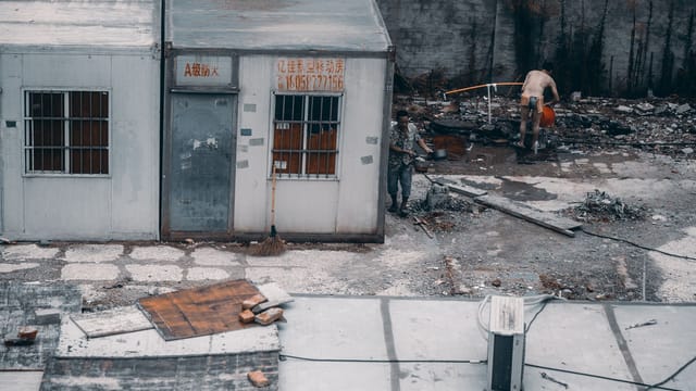 A deteriorating urban area with men working amidst debris in Hangzhou, China.