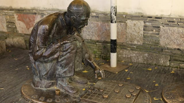 Bronze statue depicting a man playing Xiangqi, located in Nanjing, China.