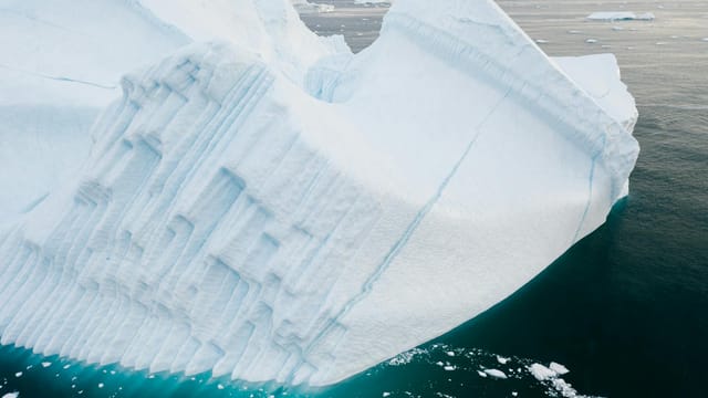 Large iceberg floating in the calm ocean showcasing natural beauty and environmental themes.