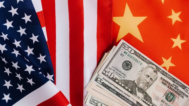 From above of United States banknotes placed on national flags of America and China illustrating international trade concept