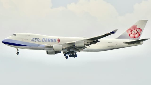 A China Airlines cargo plane flies against a cloudy sky, showcasing its iconic logo.