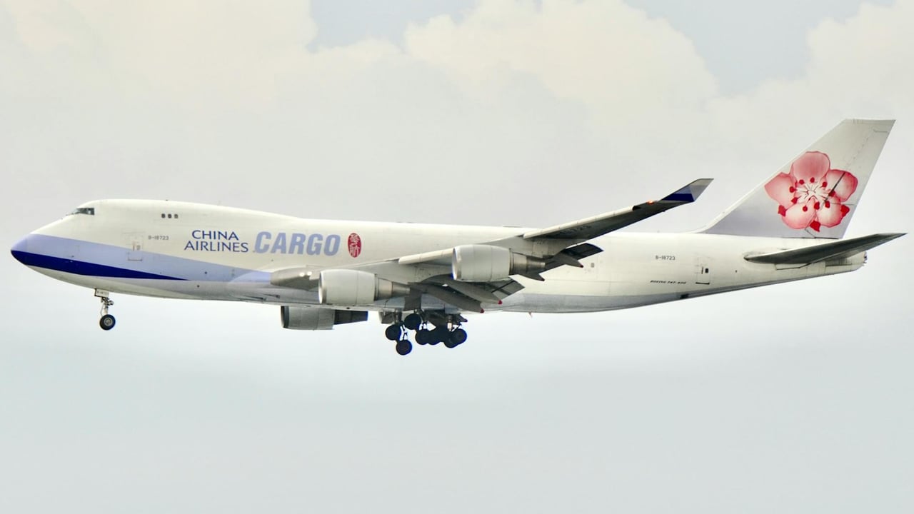 A China Airlines cargo plane flies against a cloudy sky, showcasing its iconic logo.