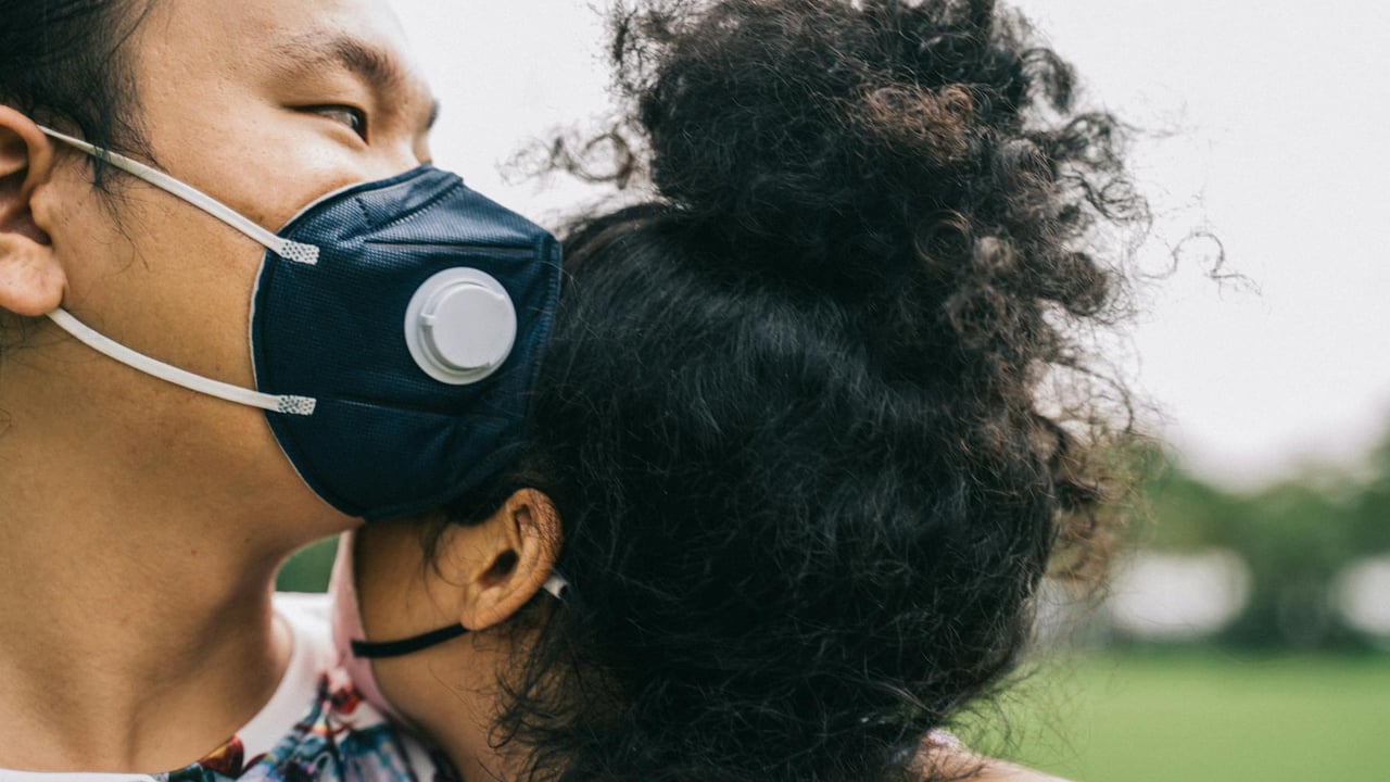 Asian couple wearing protective face masks while embracing outdoors, reflecting togetherness during a pandemic.