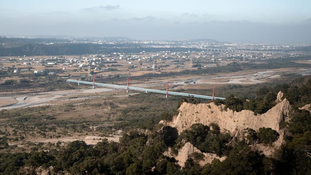 Aerial view of a bridge spanning across a vast landscape in Miaoli County.