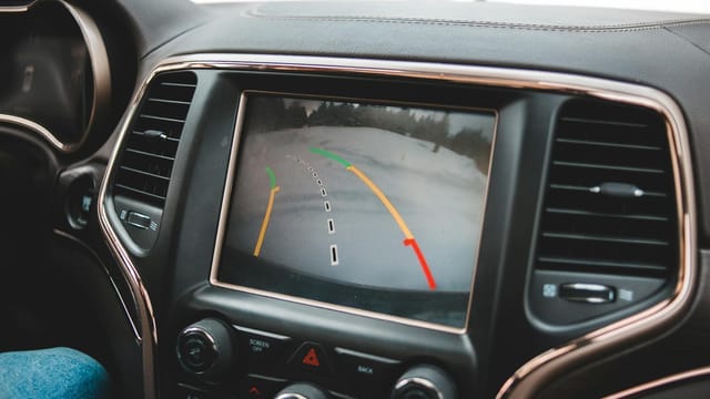 Close-up of a car's dashboard showing a rearview camera display for parking assistance.