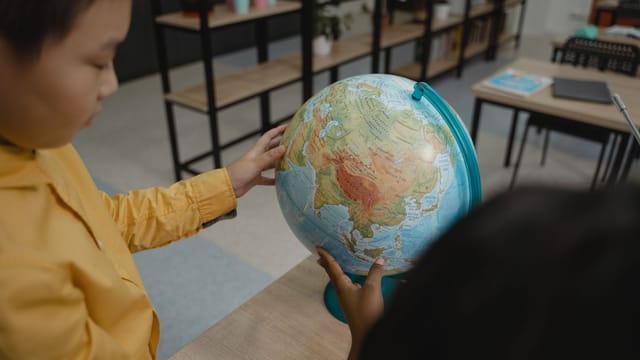 Kids explore a globe in a classroom, highlighting educational practices and curiosity.