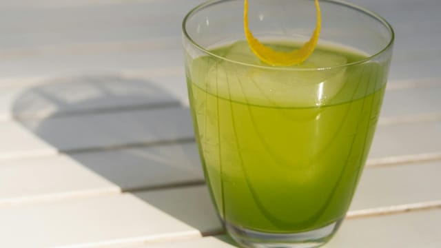 Bright green cocktail in a glass with lemon twist, perfect for summer refreshment.