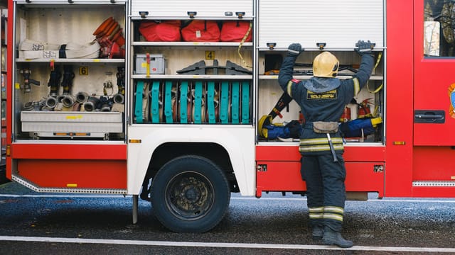 A dedicated firefighter organizing essential equipment on the side of a fire truck.