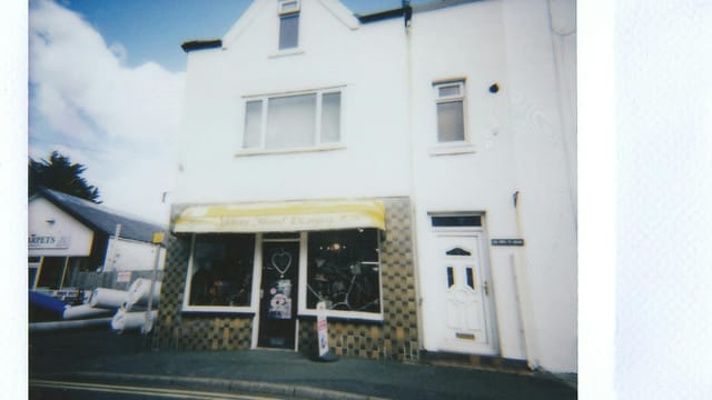 A quaint shop with a classic facade captured in an instant film style, suggesting nostalgia.