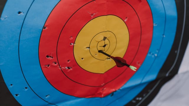 Close-up of a target in archery with a single arrow hitting the bullseye, showcasing precision and skill.