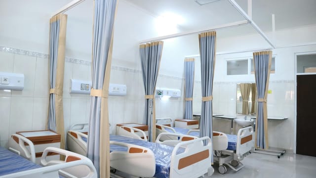 Spacious hospital ward with modern equipment and private patient areas.