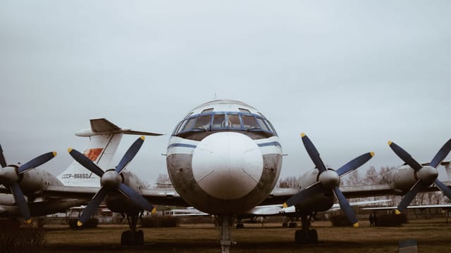 Front view of a vintage Soviet-era propeller airplane outdoors in an open-air museum setting.