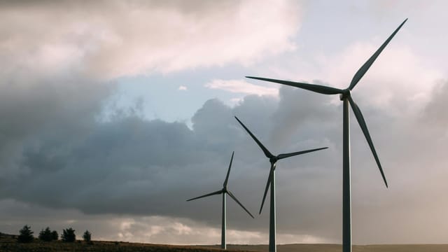 Wind turbines generating renewable energy under a dramatic cloudy sky.