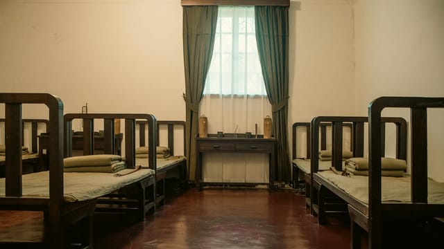 Interior view of a historic dormitory room in Meiling Palace, featuring classic wooden beds and furnishings.