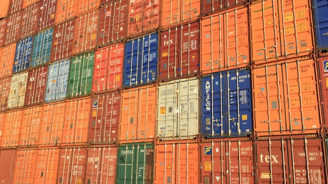 Colorful shipping containers stacked in a harbor, symbolizing global trade.
