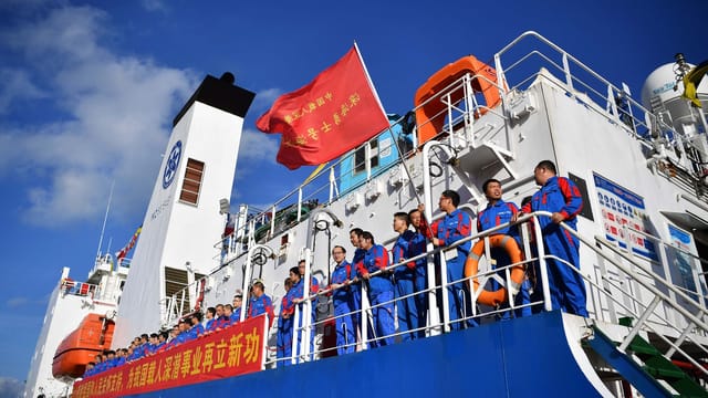 Researchers on a vessel in Sanya, China, prepare for a maritime expedition under a clear blue sky.