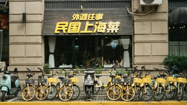 Bicycle and scooters parked outside a restaurant in vibrant Shanghai, China.