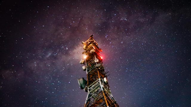 Night shot of a communication tower against a starry sky, showcasing connectivity and the cosmos.