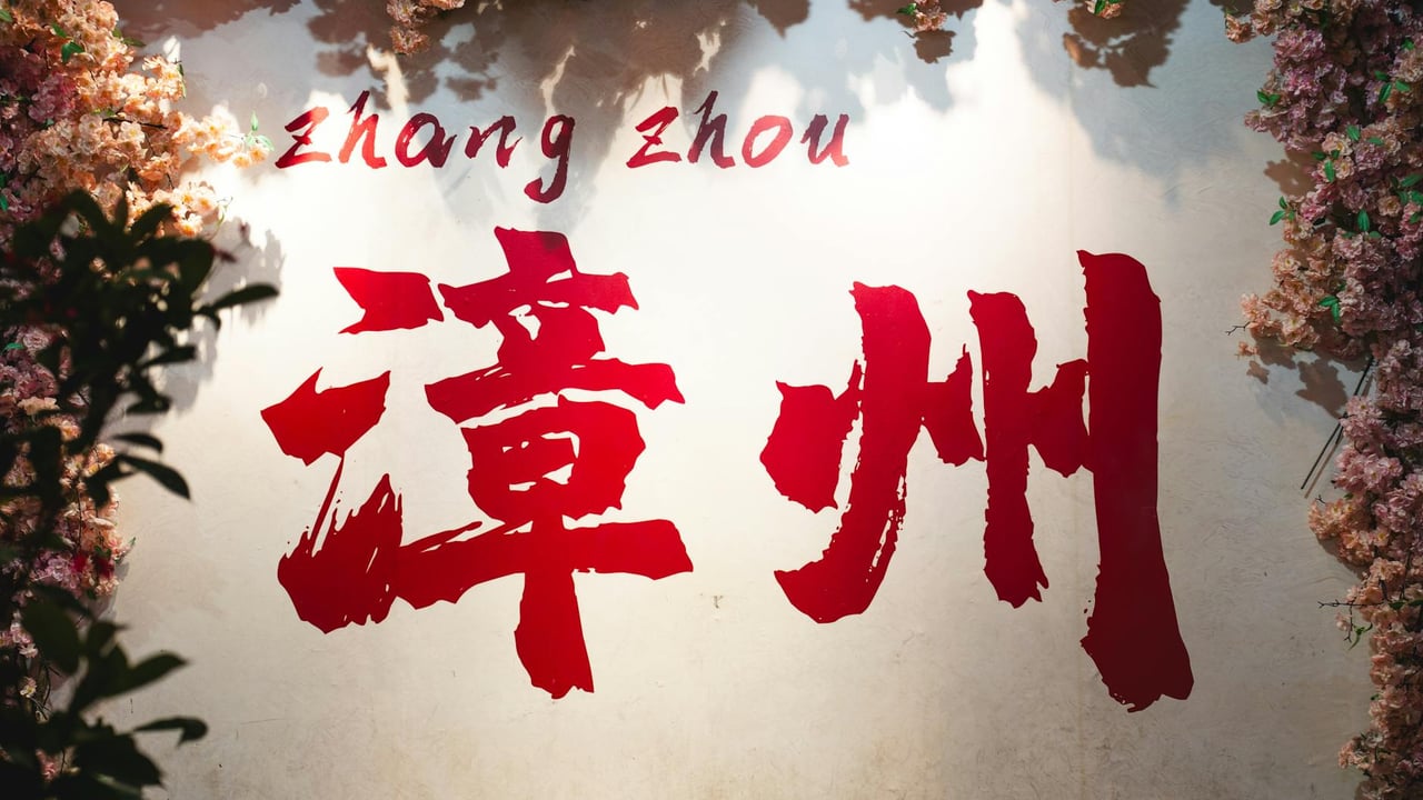 Colorful Zhangzhou sign surrounded by vibrant floral decorations, symbolizing Chinese culture and nature.