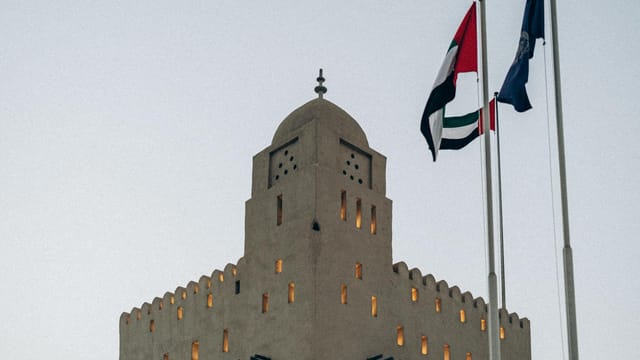 A traditional fortress with UAE flags at sunset in Abu Dhabi, showcasing architectural heritage.