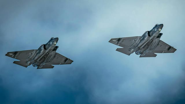 Two F-35 jets soar through cloudy skies at San Diego's airshow, showcasing military aviation excellence.