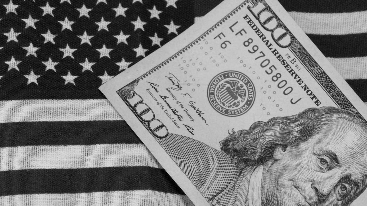 Grayscale image of US dollar bill on American flag for symbolic financial concept.