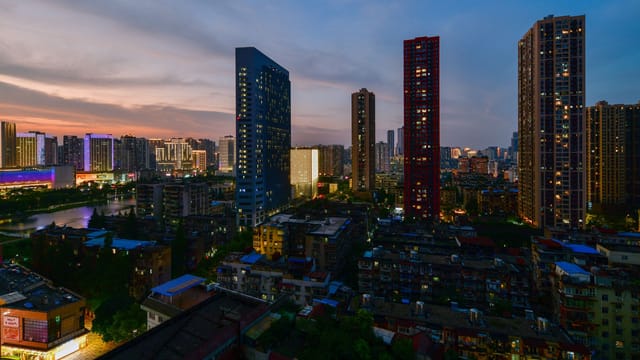 A stunning cityscape at dusk featuring illuminated skyscrapers and urban lights.
