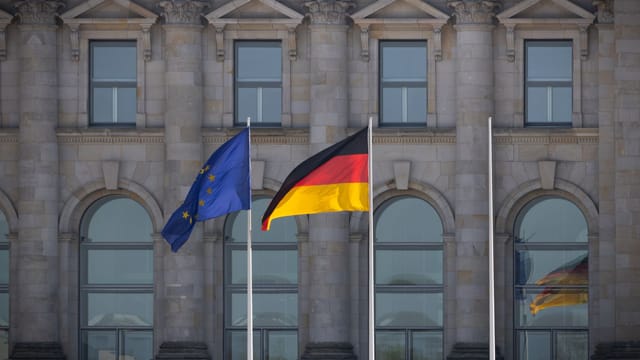 German and EU flags flying in front of the Reichstag building, Berlin, Germany.
