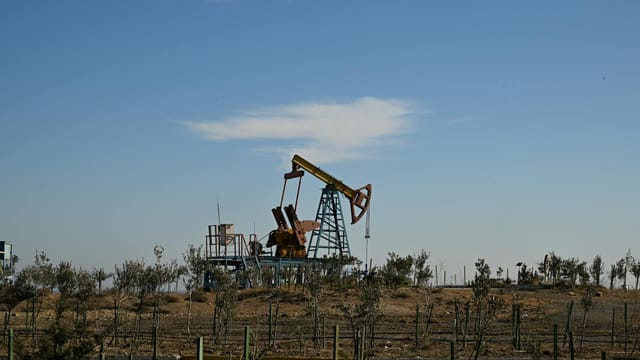 Oil pump jack in a dry landscape with shrubs and clear sky in Bakú, Azerbaijan.