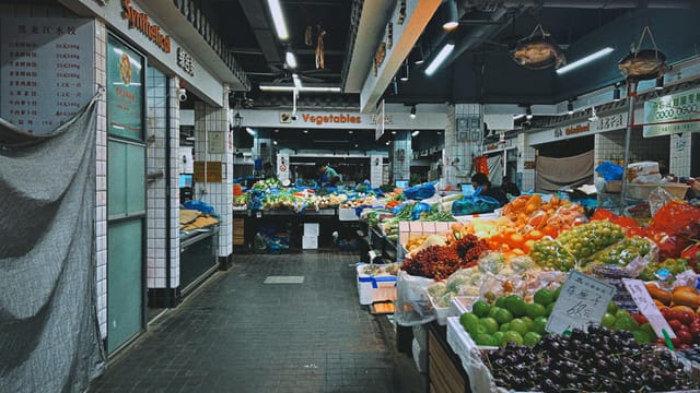 Vibrant indoor market in Shanghai showcasing fresh fruits and vegetables with diverse produce and bustling atmosphere.