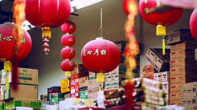 Colorful Chinese lanterns hanging amidst carton boxes with food in storage on market