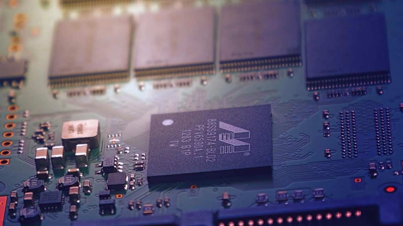 Detailed image of an electronic circuit board showing microchips and intricate wiring in a modern technological setting.