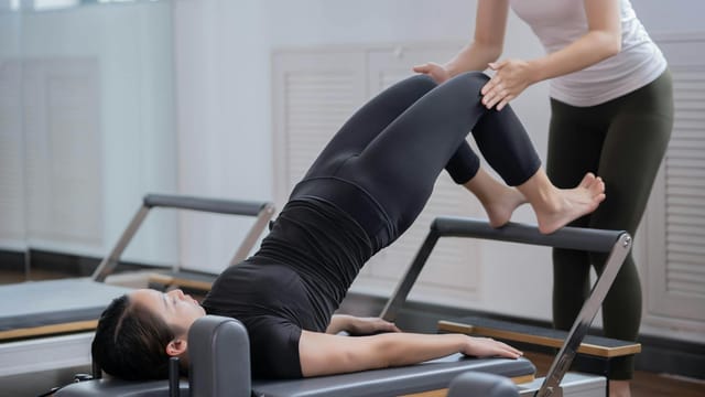 Women engaging in reformer Pilates with assistance in a Shenzhen studio promoting healthy lifestyle.